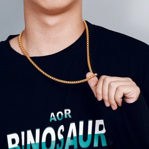Détail d'un collier à maillons circulaires dorés porté par un mannequin sur un t-shirt