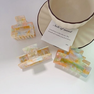 Detail of acetate hair claws featuring colorful marble patterns in a stylish setting
