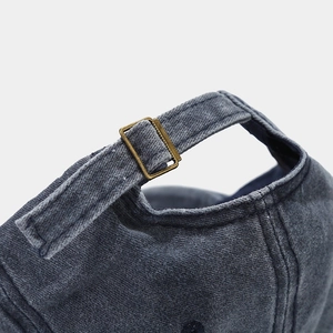 Close-up of adjustable brass metal buckle and washed denim texture on vintage baseball cap