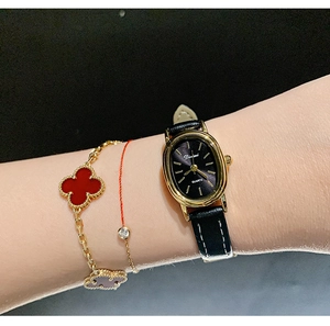 Close-up of a women's vintage oval quartz watch with black leather strap on a wrist