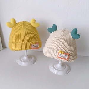 Cute knitted baby winter hats in yellow and cream with heart toppers and sun labels