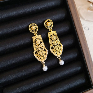 Macro view of gold hollow earrings with white pearls in a black velvet jewelry box