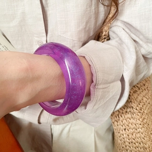 Detail of purple resin bangle with blue glitter flakes worn on wrist during vacation