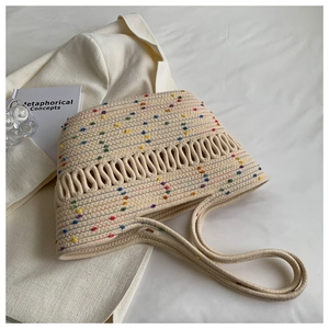 Detail of woven tote bag with colorful embroidered dots on a textured beige surface