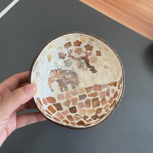 Detail of a handmade coconut shell bowl featuring a mother-of-pearl elephant inlay