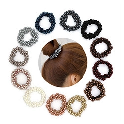 Dettaglio di dodici elastici per capelli in perle multicolori disposti attorno allo stile