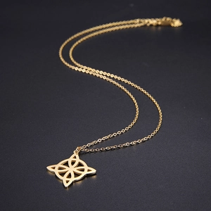 Detailed view of polished gold compass flower pendant on black matte background