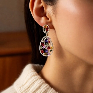 Close-up of vintage gold earrings with colorful zircon stones on model's ear