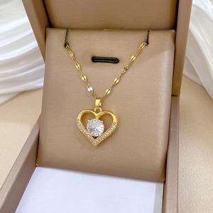 Close-up of heart-shaped gold necklace with large zircon and side diamonds in a gift box