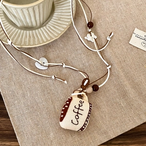 Detail of coffee theme necklace featuring canvas mini cup pendant with wooden beads