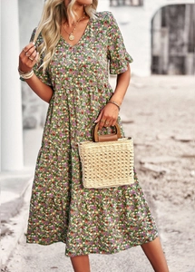 Close-up of green floral V-neck dress paired with a stylish woven handbag in outdoor setting