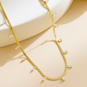 Close-up of golden snake chain necklace with rectangular zircon stones in luxury style