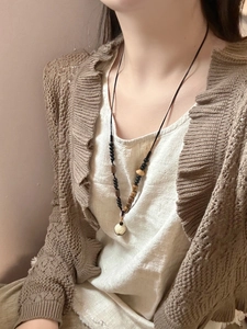Gros plan d'un collier ethnique long avec perles noires et pendentif blanc sur mannequin