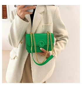 Detail of green square shoulder bag featuring gold chain strap and circular buckle accent