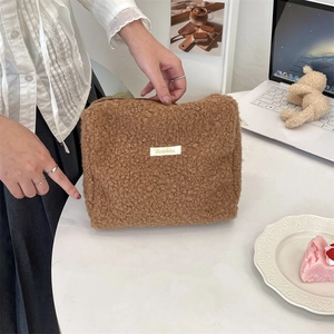 Bruine pluizige make-uptas van teddy stof met Snakka-label op gezellig bureau