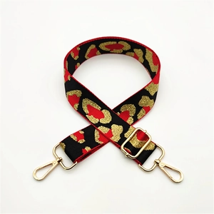 Detail of adjustable leopard print bag strap with red, black, and gold woven texture