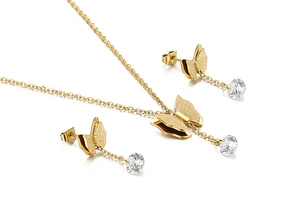 Macro detail of gold butterfly jewelry set with textured finish and clear round gemstones