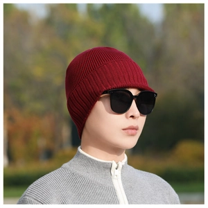 Detail of burgundy knit beanie with visor showing warm ribbed texture on a male model