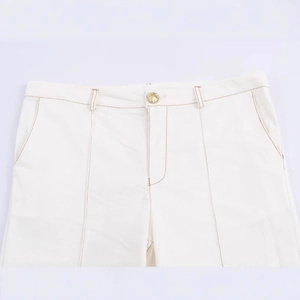 White high-waisted flared pants with brown contrast stitching and golden button detail