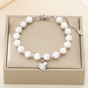 Close-up of stainless steel heart charm and white pearl bracelet on jewelry box