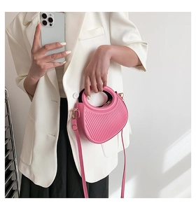 Detailed close-up of pink ruched saddle bag with circular handle and thin strap