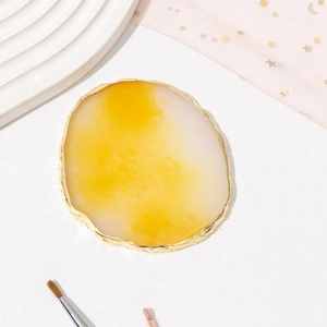 Close-up of resin agate nail art palette with gold rim and yellow marble texture