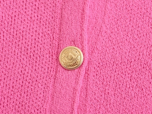 Macro view of vintage gold crest button on pink knit cardigan with smooth texture