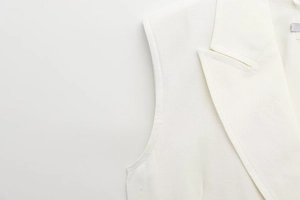 Detailed close-up of the elegant white vest dress neckline and fabric texture