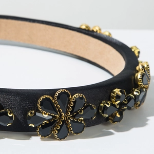 Détail du serre-tête baroque avec fleurs en strass noirs sur tissu de satin