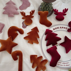 Flat lay of vintage velvet Christmas ornaments in star, tree, and deer shapes on white cloth