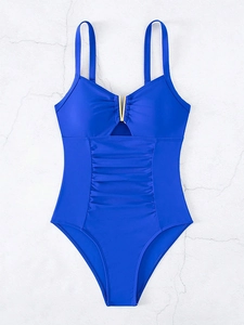 Detail of royal blue one-piece swimsuit with gold V-hardware and ruched slimming texture