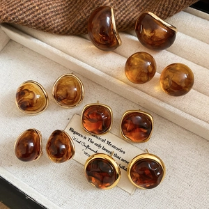 Close-up of vintage resin earrings with gold edges in geometric amber and brown tones