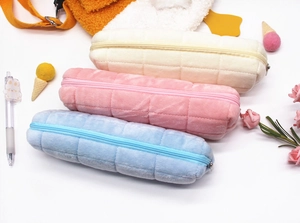 Close-up of plush quilted pencil cases in beige, pink and blue with smooth zippers