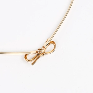 Close-up of golden elastic metal waist belt featuring a detailed bow-shaped buckle