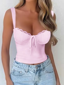 Vista detallada de un top corto rosa con cordones, costuras de encaje y lazo decorativo