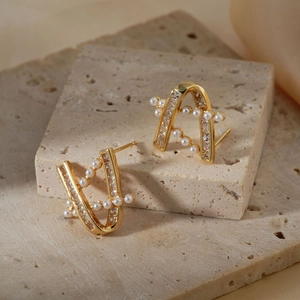 Elegant gold-plated V-shaped pearl stud earrings with zircon accents on stone surface