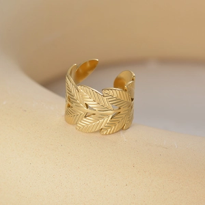 Close-up of golden hollow leaf adjustable ring with detailed vein texture on ceramic base