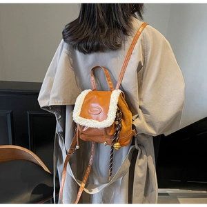 Rear view of a model wearing the brown and white faux shearling mini backpack on stairs