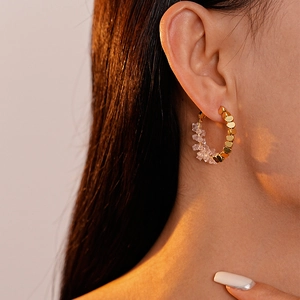 Détail de boucles d'oreilles en cristal couleur bonbon et perles dorées sur un modèle