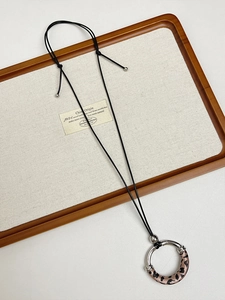Detail of adjustable black cord necklace with pink leopard print fabric metal pendant