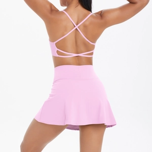 Vue détaillée du dos d'un ensemble de yoga rose avec bretelles croisées et jupe de tennis