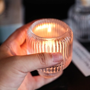 Handheld ribbed clear glass candle holder with warm lit candle for romantic table setting