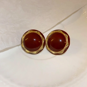 Deep red resin heart earrings with textured golden metal base on white background