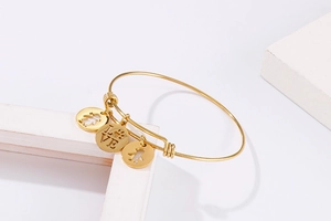 Macro shot of gold-plated adjustable bracelet with LOVE charms and cutout figure pendants