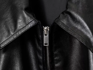 Detaillierte Nahaufnahme von Kragen und Metallreißverschluss der schwarzen Kunstlederjacke