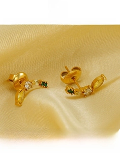 Détail macro du clou d'oreille banane en acier titane doré avec pierres jaune et verte