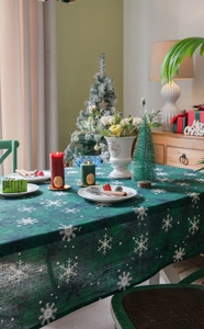 Détail de la nappe de Noël verte avec flocons de neige blancs et décor festif chic
