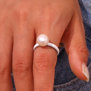 Minimalist white enamel dome ring with white pearl on blue denim background