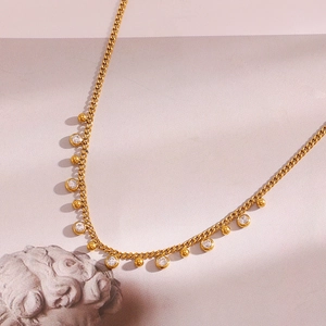 Detail of 18K gold-plated curb chain necklace with sparkling zircon and golden beads