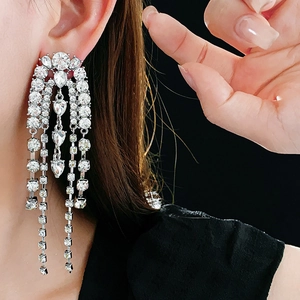 Detail of silver drop earrings with shimmering rhinestone tassels on a model